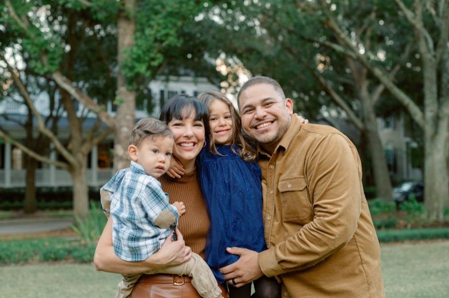 A young family of four smiling together outdoors