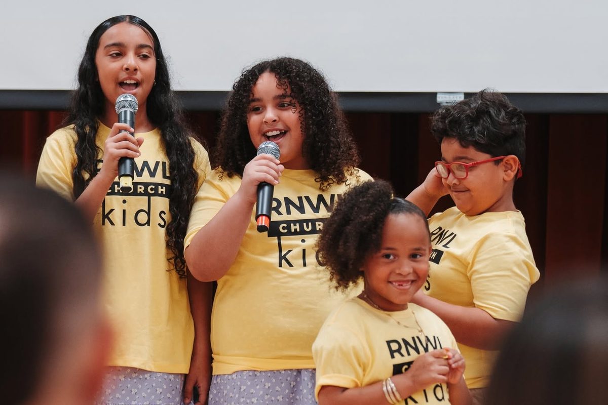 Four Renewal Kids in yellow shirts singing on a Sunday, two on microphones