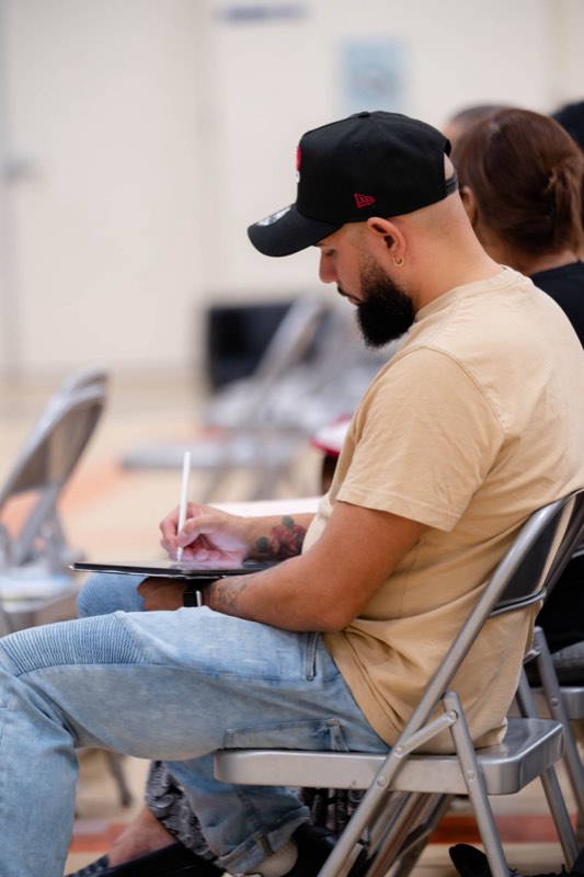 A man in a cap taking notes on a tablet during the message